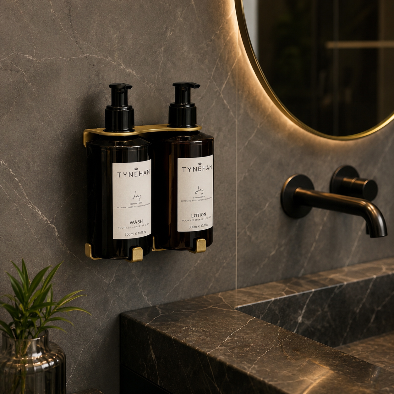 Two Tyneham amber bottles labeled 'Wash' and 'Lotion' on a gold wall-mounted holder in a bathroom setting.