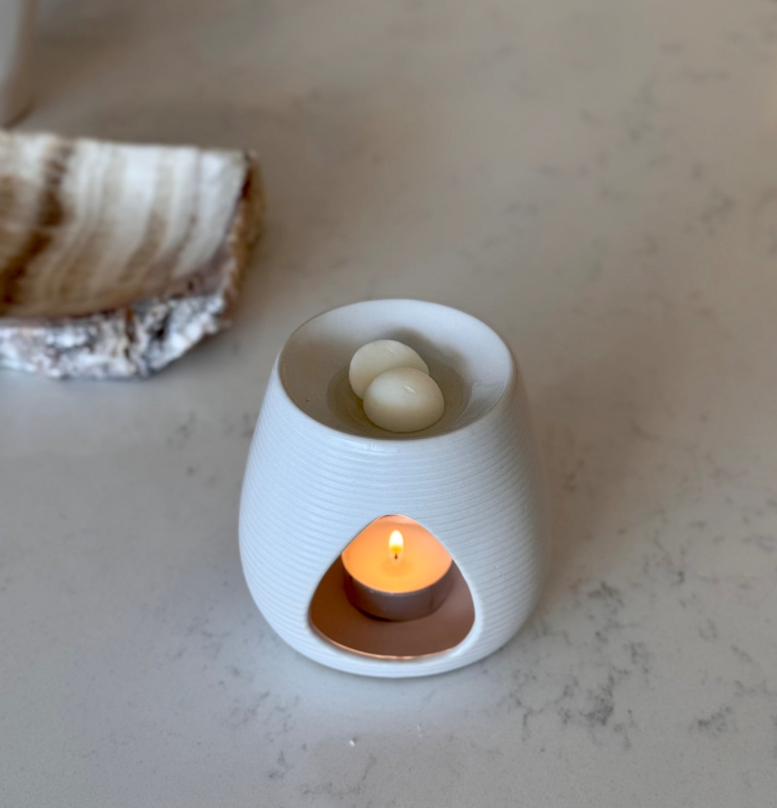 White ceramic wax melt burner with texture on a white surface